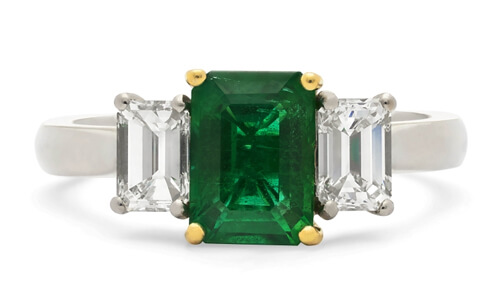 3 stone ring with emerald center stone and yellow prongs, diamond side stones with white gold prongs